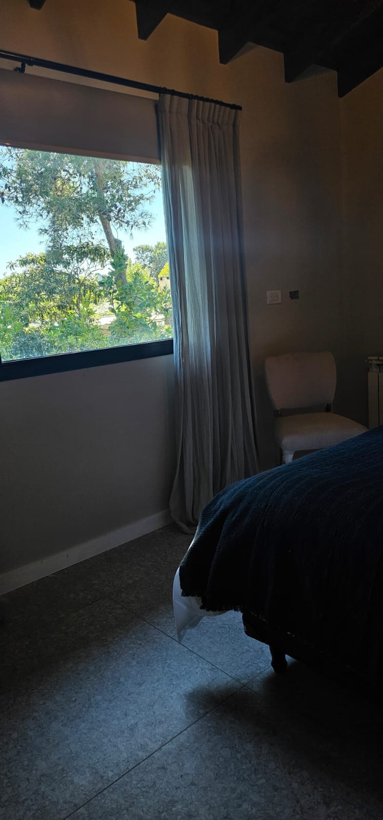 Cortinado de tela en dormitorio con vista al jardín