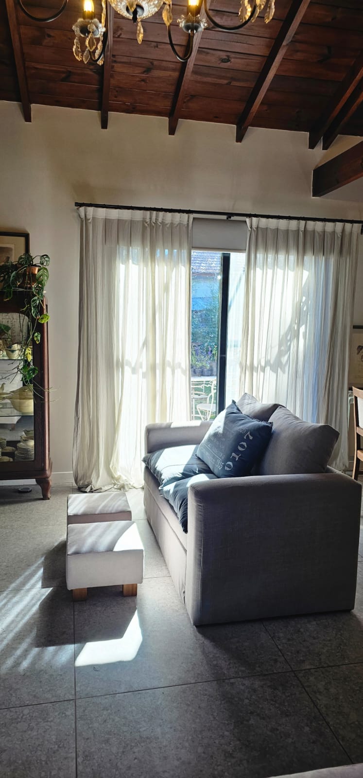 Cortinado de tela natural en living con techo de madera