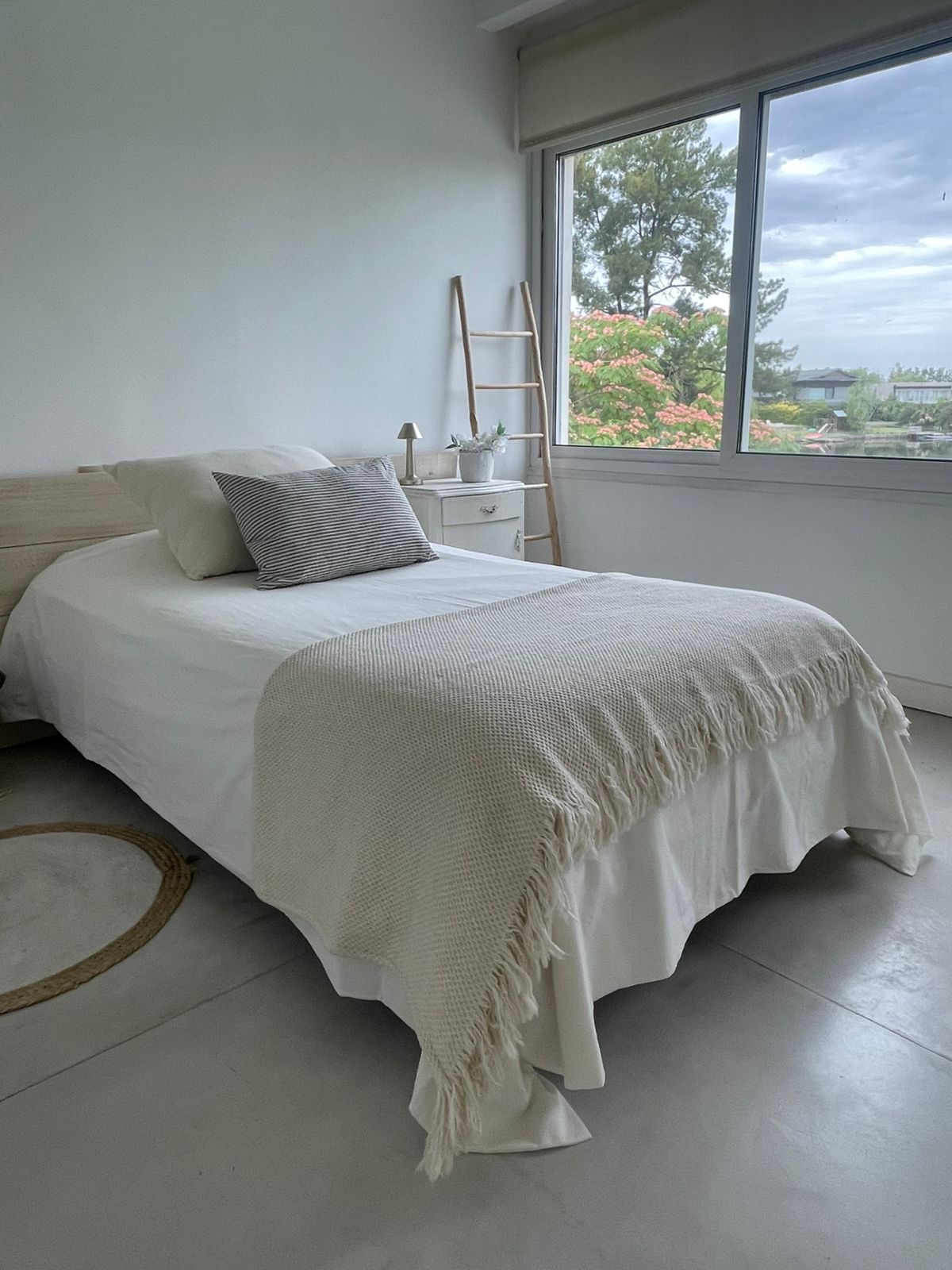 Dormitorio amplio con ropa de cama y cortina roller blanca